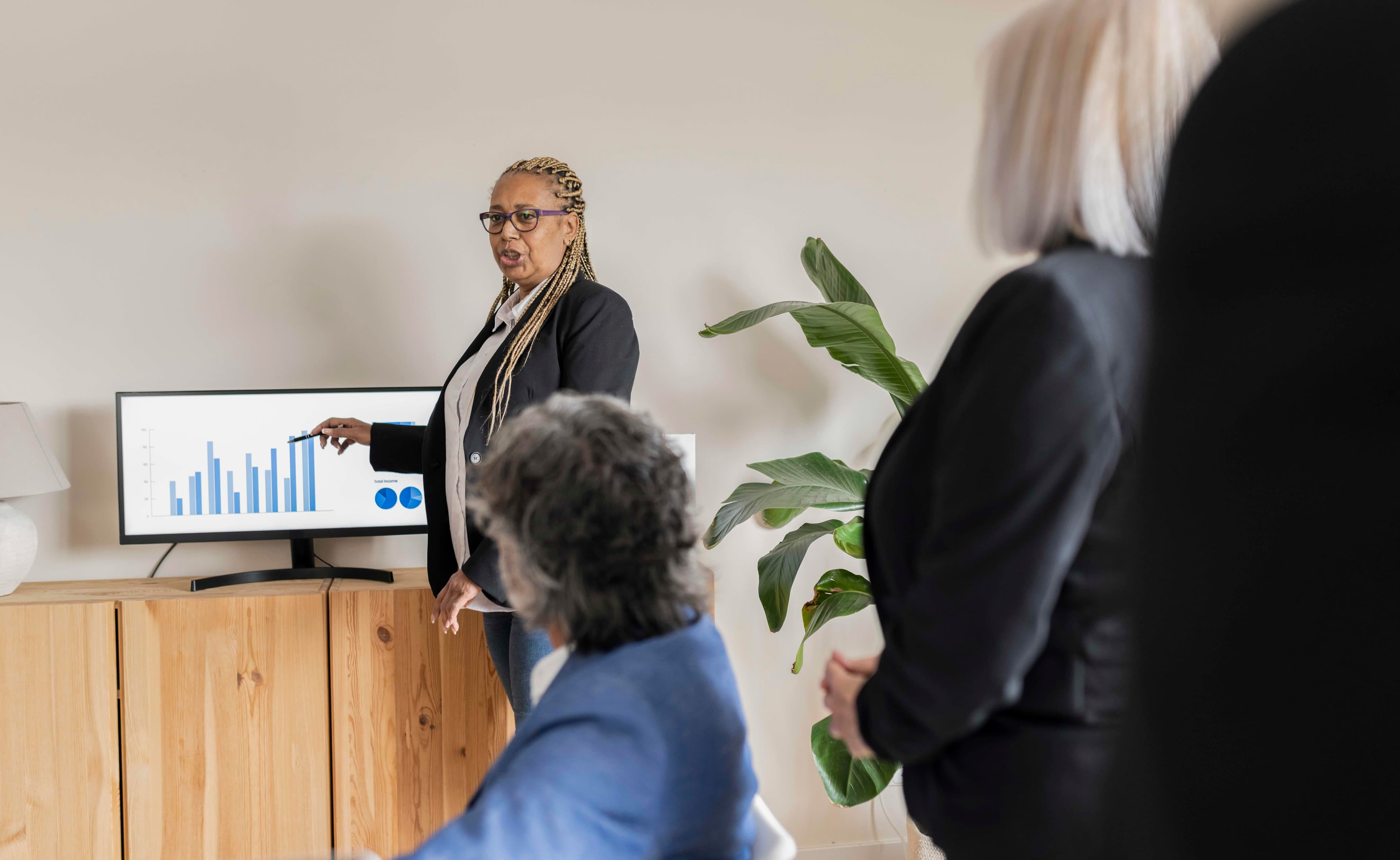 A business presentation displaying data charts on a screen in a modern office, representing how operations leaders use QReserve’s analytics to present utilization metrics and data-driven insights to stakeholders.