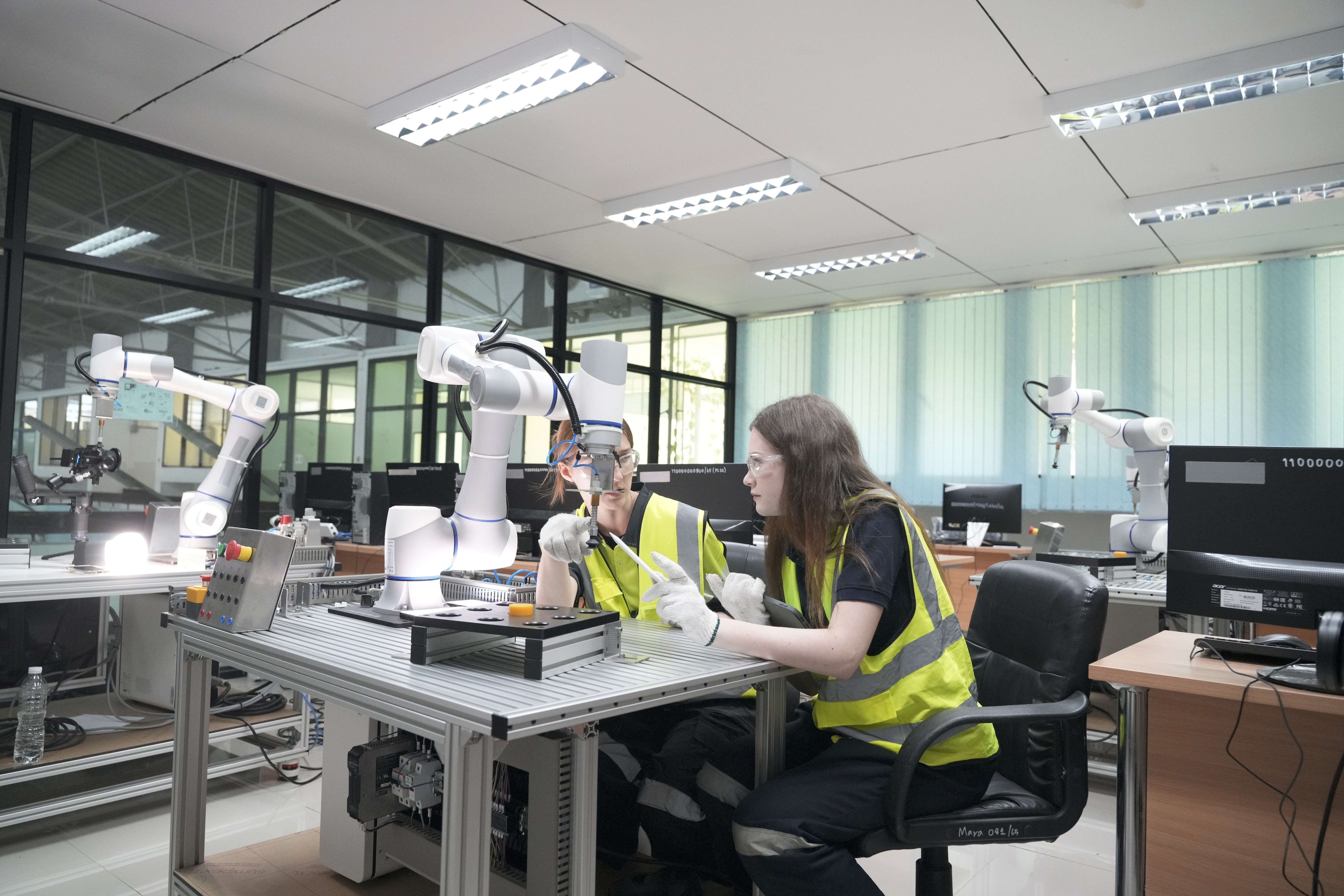 Engineers working alongside advanced robotics in a modern factory setting, representing QReserve’s capability to coordinate complex scheduling, enforce safety certifications, and track downtime for automated manufacturing assets.